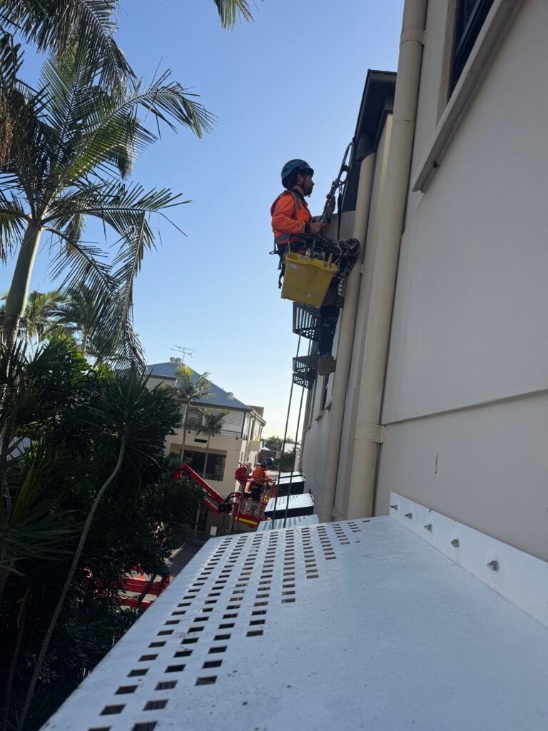 High Property Access rope access technician painting the exterior wall of an apartment building
