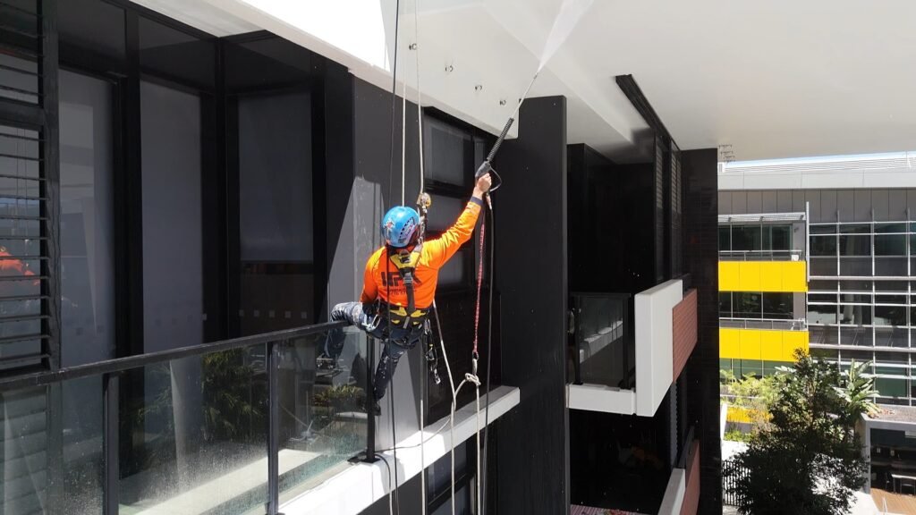 High Property Access technician cleaning façade glass by rope access at 9 Edmondstone St, South Brisbane