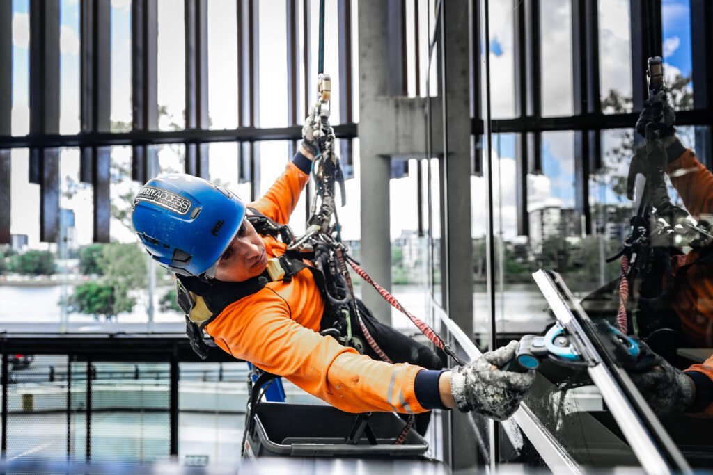 High Property Access rope access technician cleaning commercial glass windows